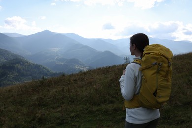 Tourist with backpack enjoying mountain landscape, back view. Space for text