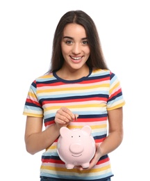 Photo of Portrait of young woman putting coin into piggy bank on white background