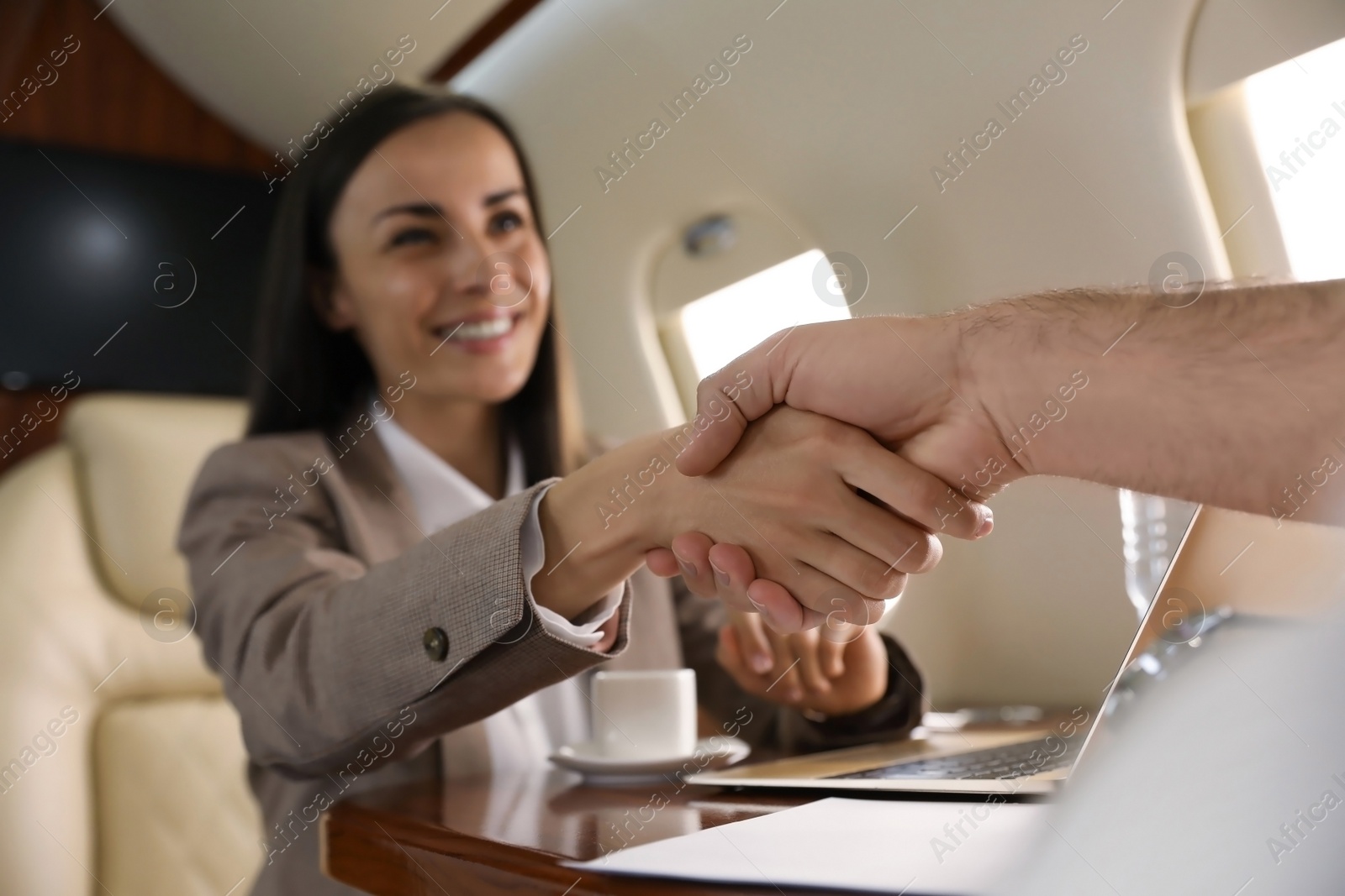 Photo of Colleagues shaking hands in airplane during flight