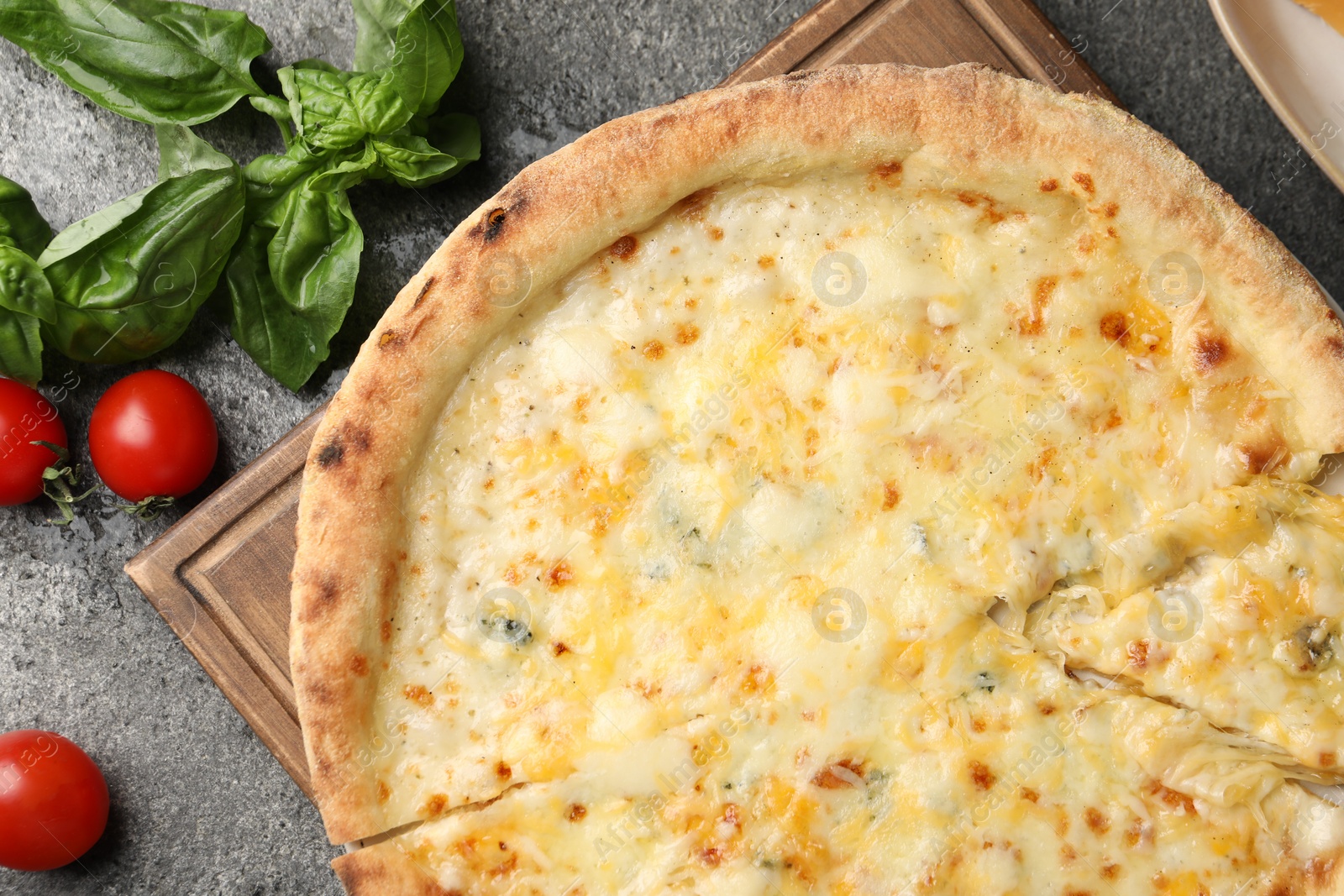 Photo of Delicious cheese pizza, basil and tomatoes on dark grey table, flat lay