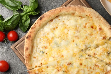 Photo of Delicious cheese pizza, basil and tomatoes on dark grey table, flat lay