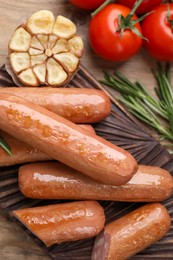 Photo of Delicious vegan sausages, garlic and tomatoes on wooden table, flat lay