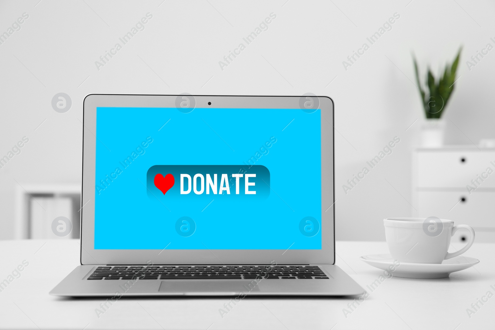 Image of Laptop with text DONATE on white table in office