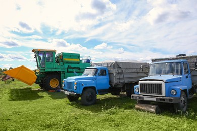 Photo of Modern combine harvester and old trucks on green lawn with fresh grass