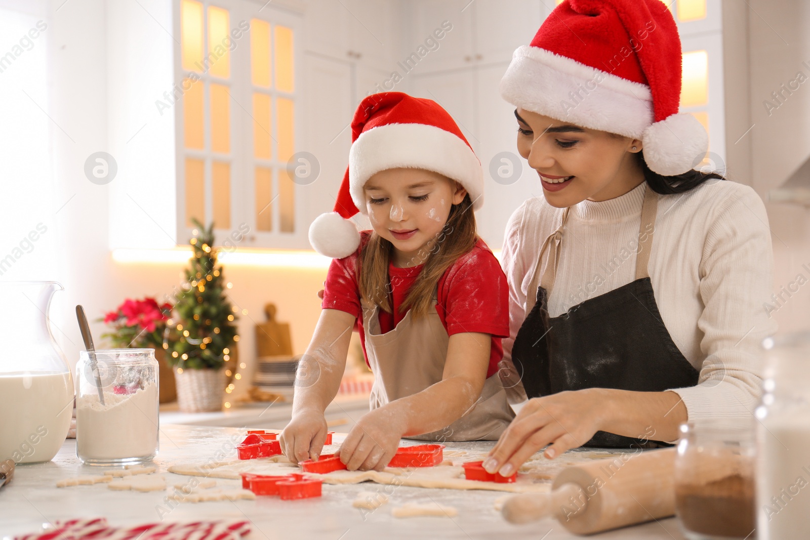 Photo of Mother with her cute little daughter making Christmas cookies in kitchen