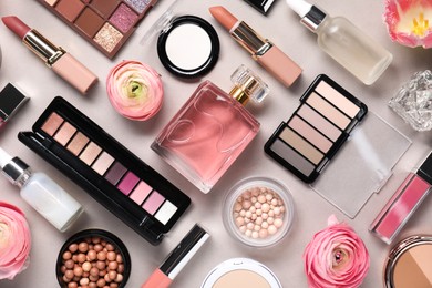 Flat lay composition with different makeup products and beautiful spring flowers on grey background