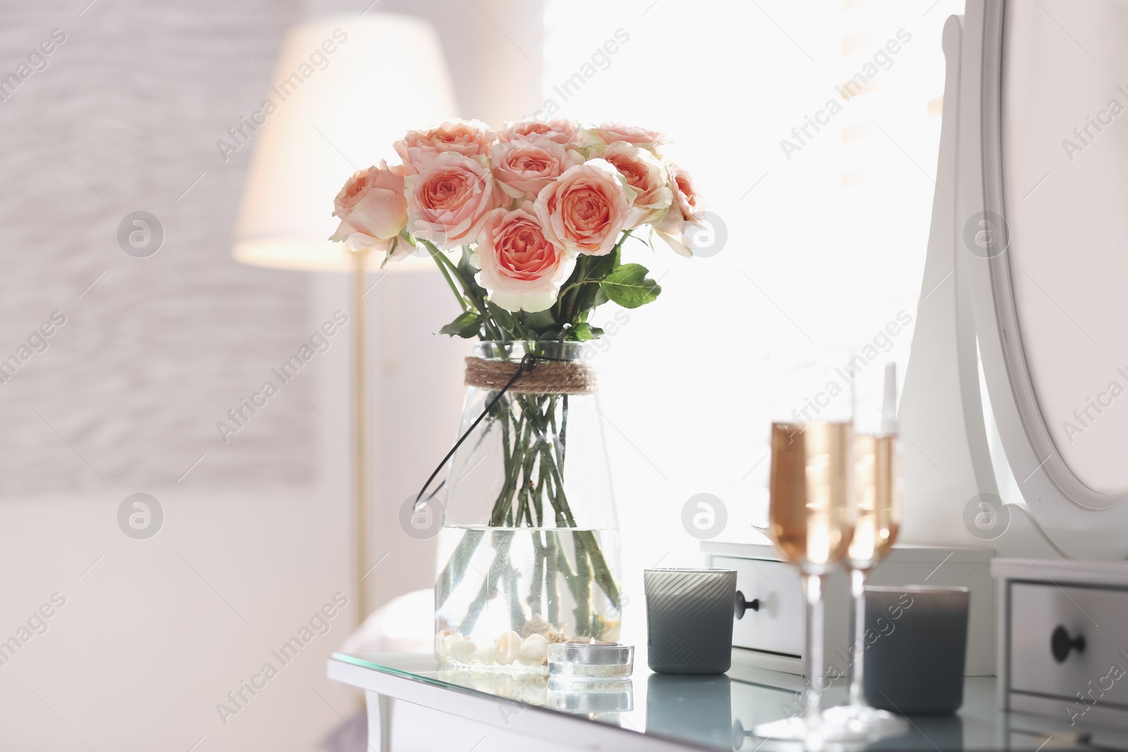 Photo of Glass vase with beautiful flowers on dressing table in modern room interior