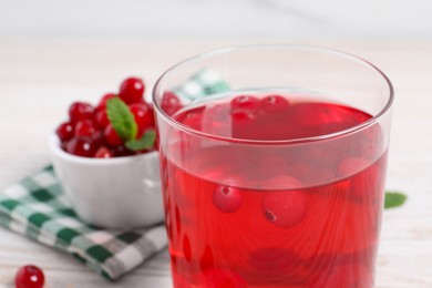 Photo of Tasty cranberry juice in glass on white table, closeup