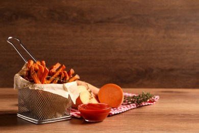 Photo of Sweet potato fries and ketchup on wooden table, space for text