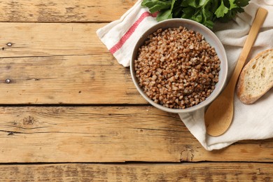 Tasty buckwheat in bowl served on wooden table, flat lay. Space for text