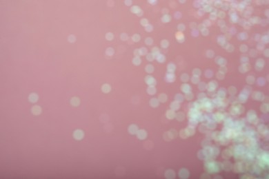 Photo of Blurred view of white glitter on pink background. Bokeh effect