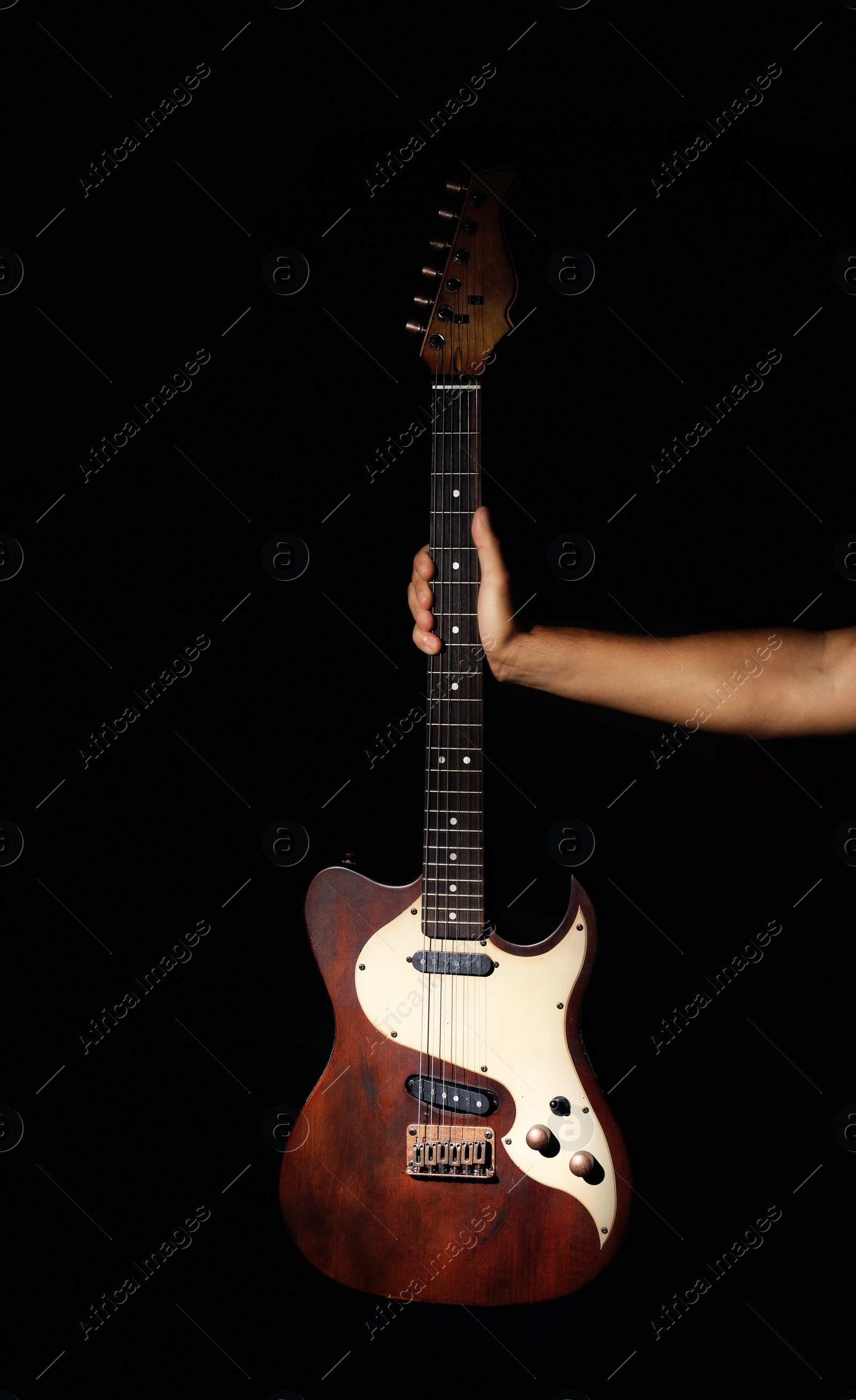 Photo of Man holding electric guitar on black background, closeup