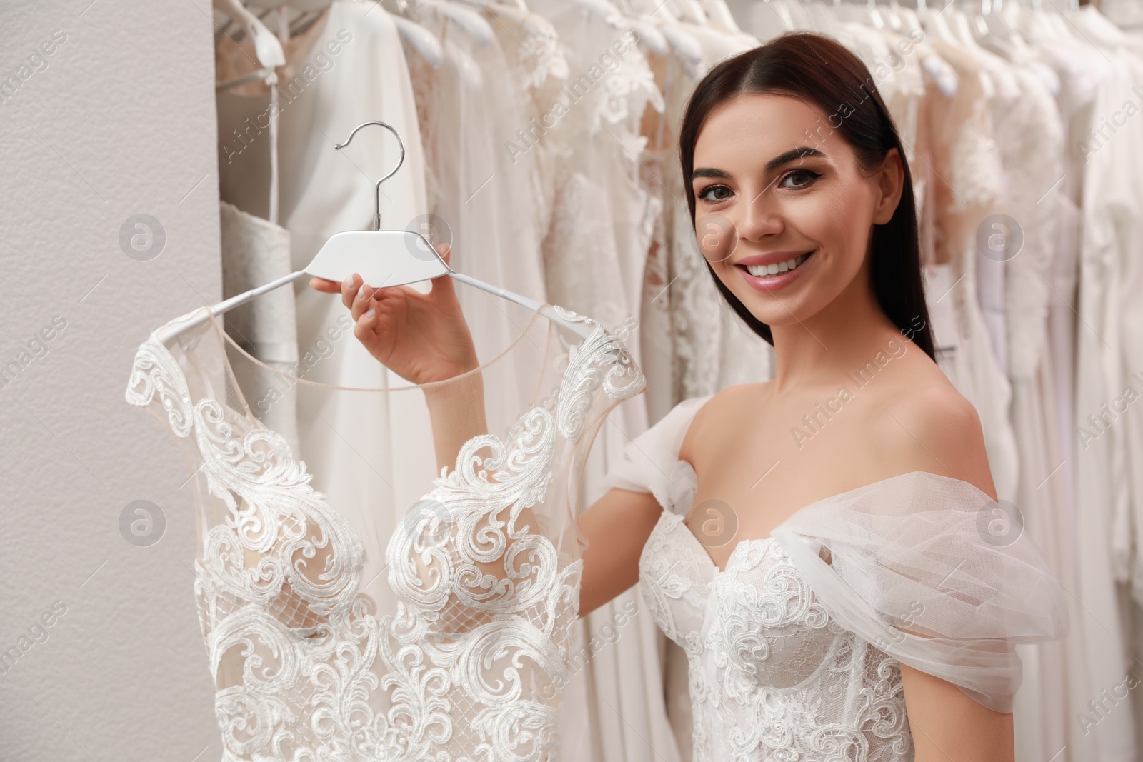 Photo of Young woman choosing wedding dress in salon