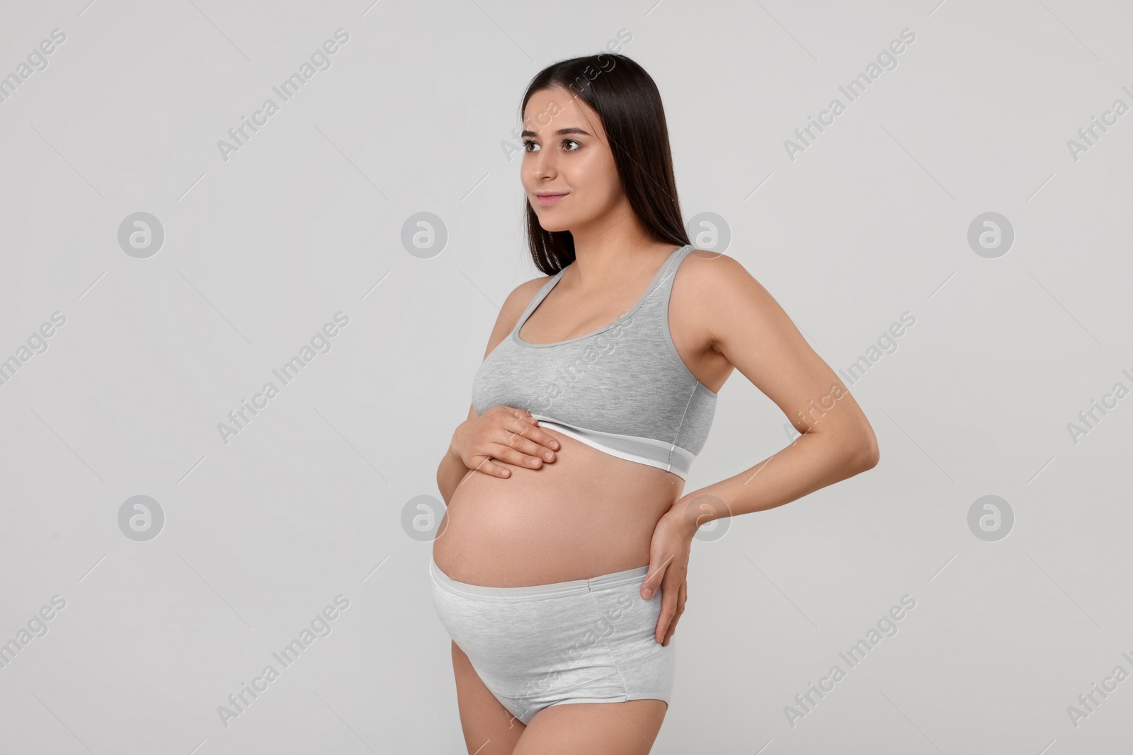 Photo of Beautiful pregnant woman in comfortable maternity underwear on grey background