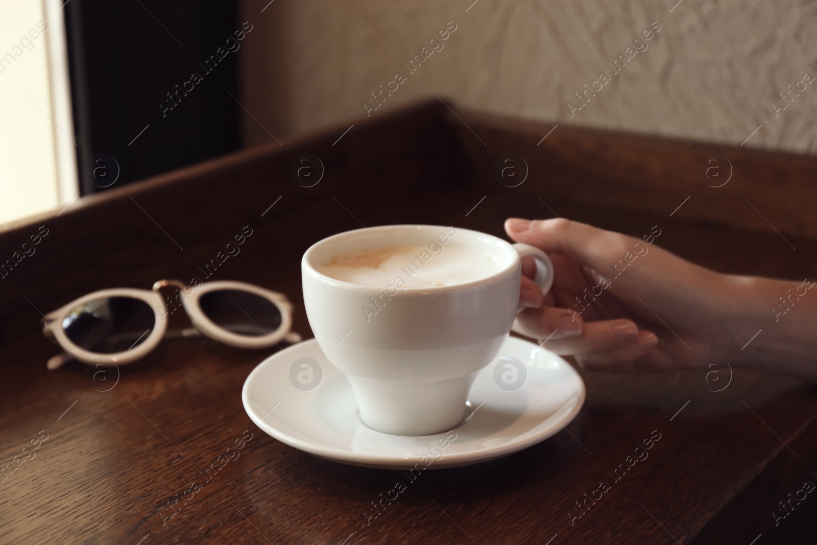 Photo of Woman with cup of fresh aromatic coffee at table