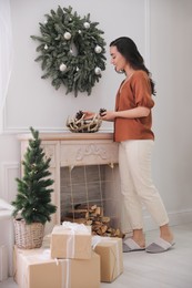 Photo of Woman decorating home interior with conifer cones
