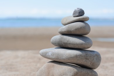Photo of Stack of stones on beautiful sandy beach near sea, closeup. Space for text