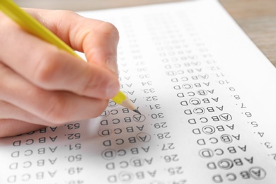 Student filling answer sheet at table, closeup