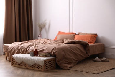 Photo of Bed with orange and brown linens in stylish room