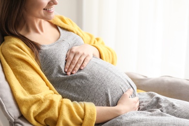 Young pregnant woman resting in armchair at home