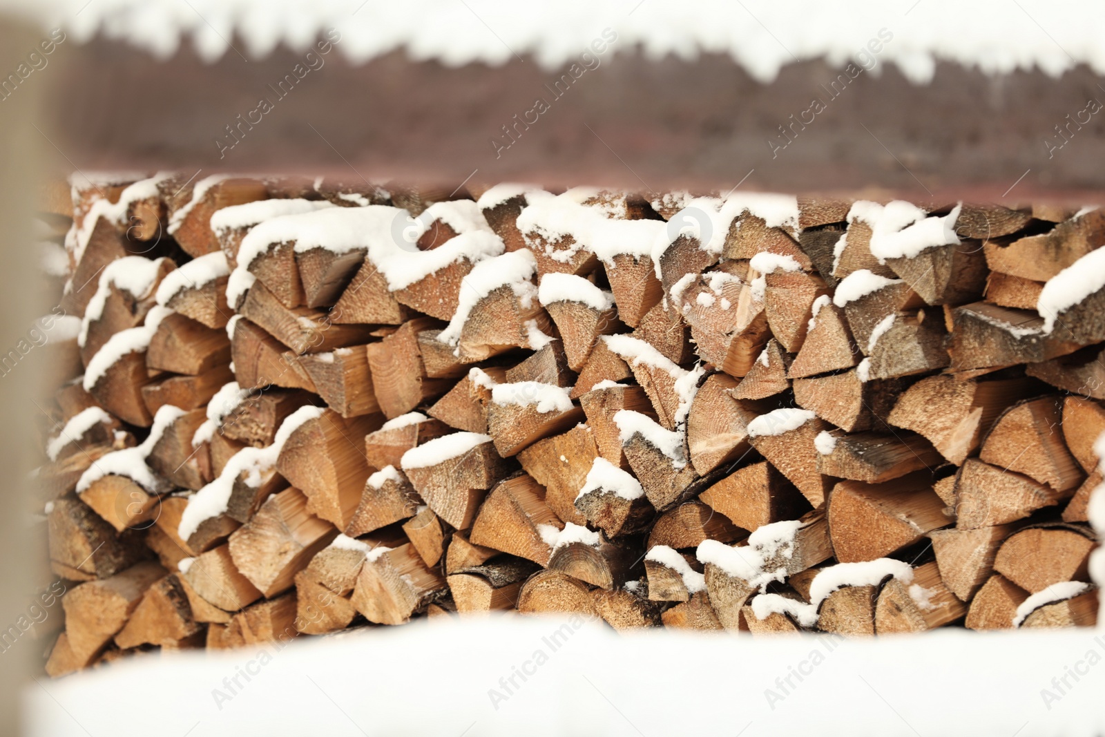 Photo of Large pile of firewood covered with snow outdoors