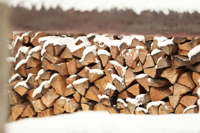 Large pile of firewood covered with snow outdoors