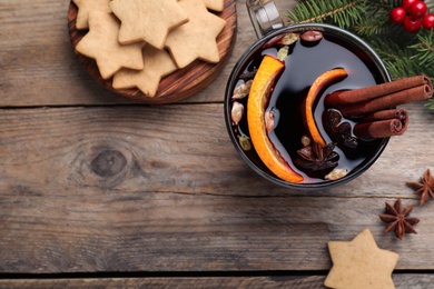 Flat lay composition with aromatic mulled wine on wooden table, space for text