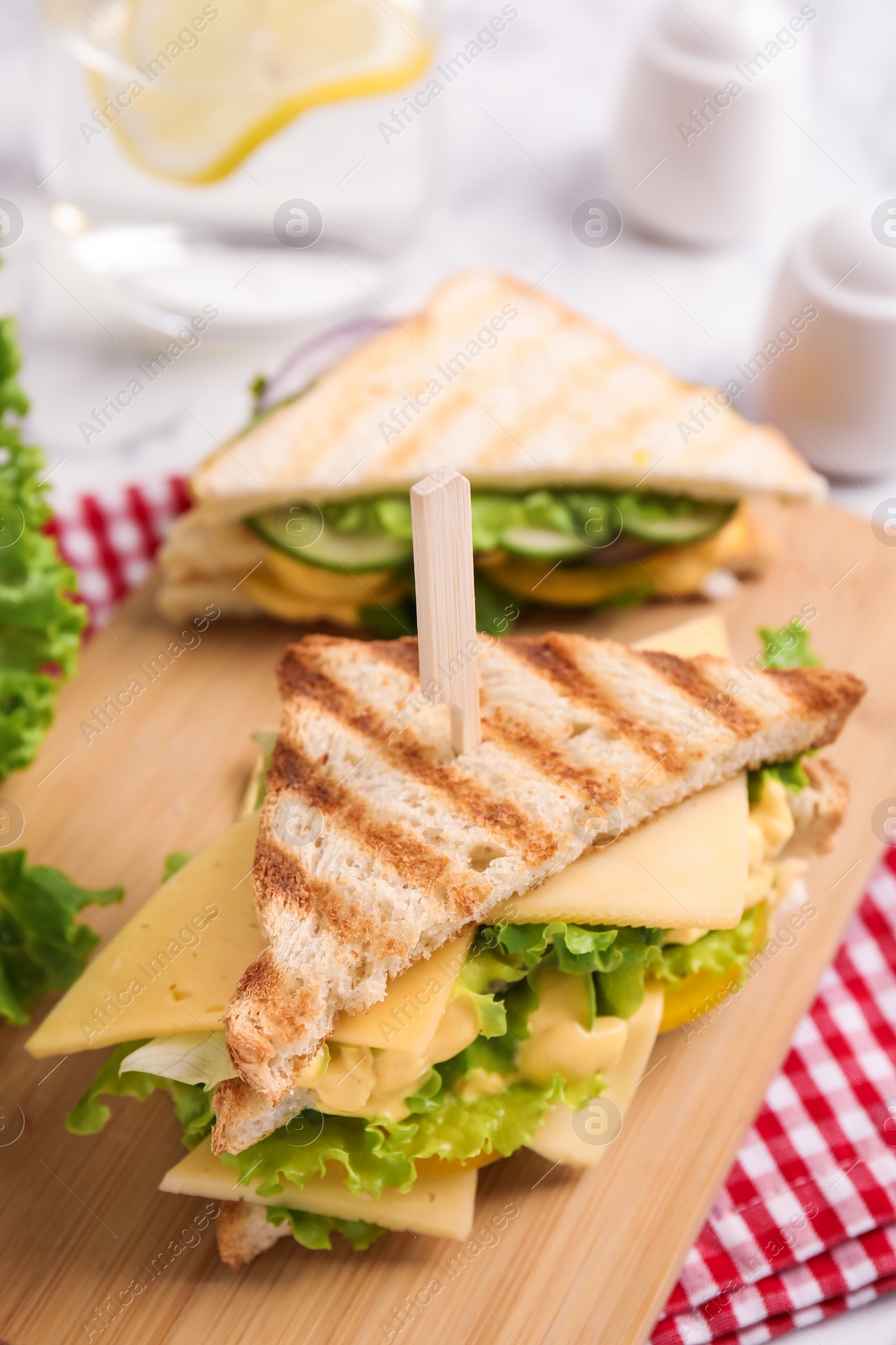 Photo of Wooden board with tasty cheese sandwich on table