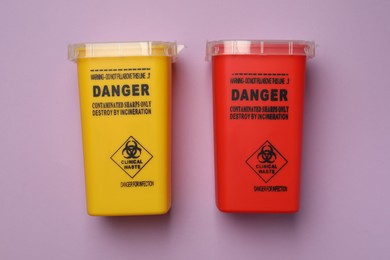 Photo of Sharps containers for used syringe on violet background, flat lay