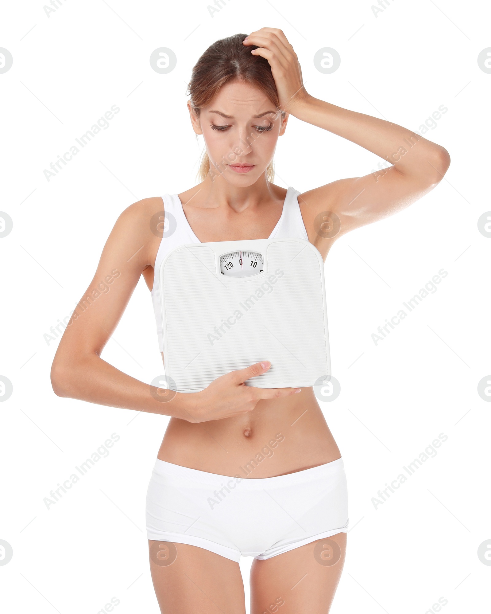 Photo of Worried young woman holding bathroom scales on white background. Weight loss diet