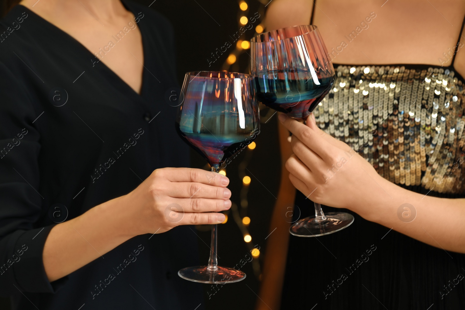 Photo of Women clinking glasses of red wine at party, closeup