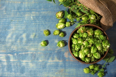 Photo of Fresh green hops in bowl on wooden background, top view with space for text. Beer production