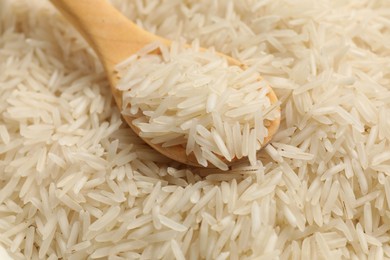 Photo of Heap of raw basmati rice with spoon, closeup