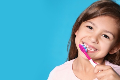 Portrait of little girl with toothbrush on color background. Space for text