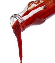 Photo of Pouring tasty red ketchup from glass bottle isolated on white
