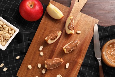 Slices of fresh apple with nut butter and peanuts on wooden table, flat lay