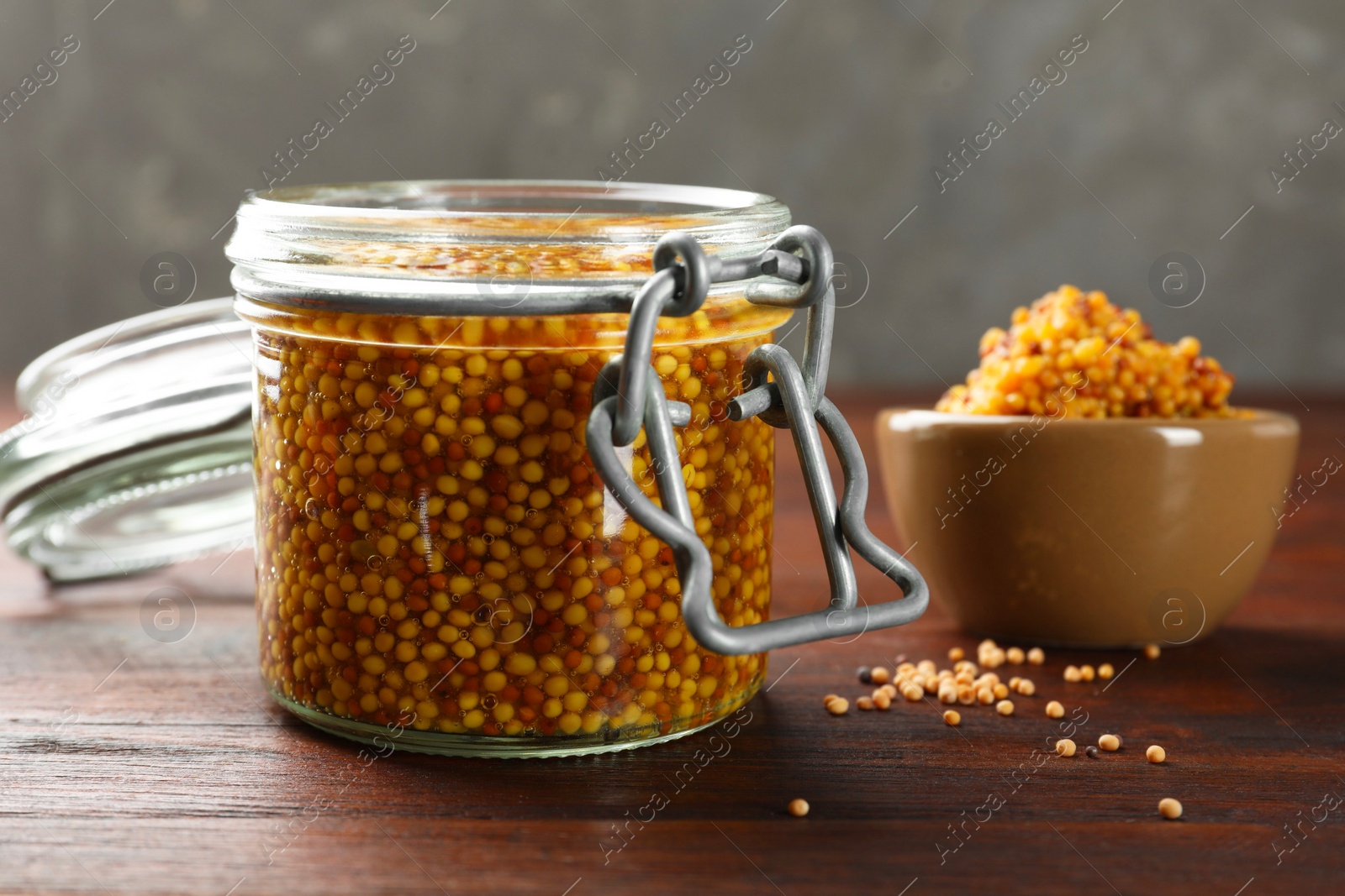 Photo of Whole grain mustard in jar on wooden table, closeup