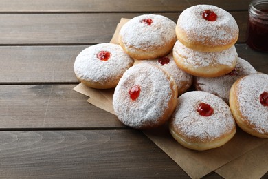 Photo of Many delicious donuts with jelly and powdered sugar on wooden table. Space for text