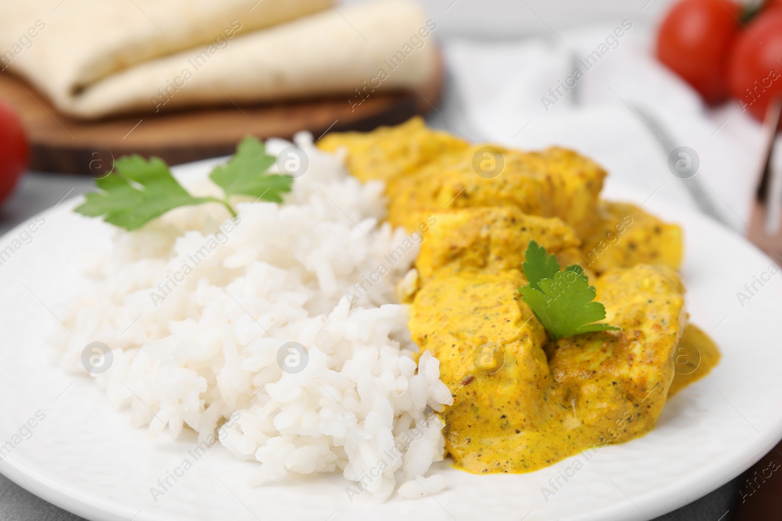 Photo of Delicious rice and chicken with curry sauce on plate, closeup