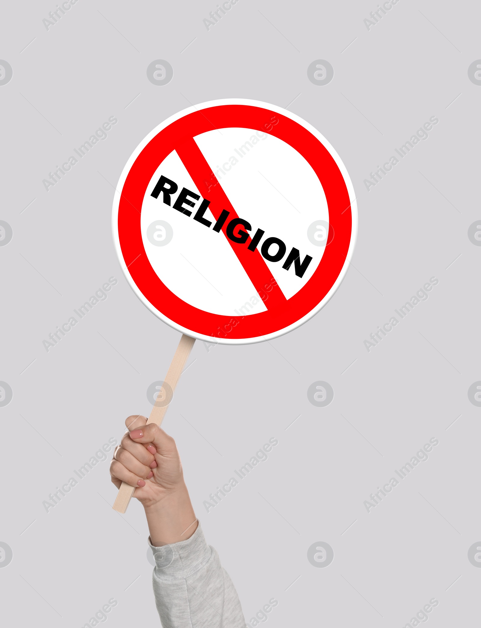 Image of Atheism concept. Woman holding prohibition sign with crossed out word Religion on light grey background