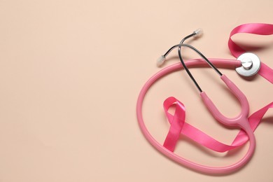 Breast cancer awareness. Pink ribbon and stethoscope on beige background, flat lay. Space for text