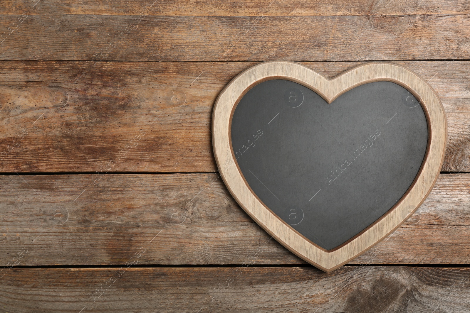 Photo of Heart shaped chalkboard on wooden background, top view with space for text