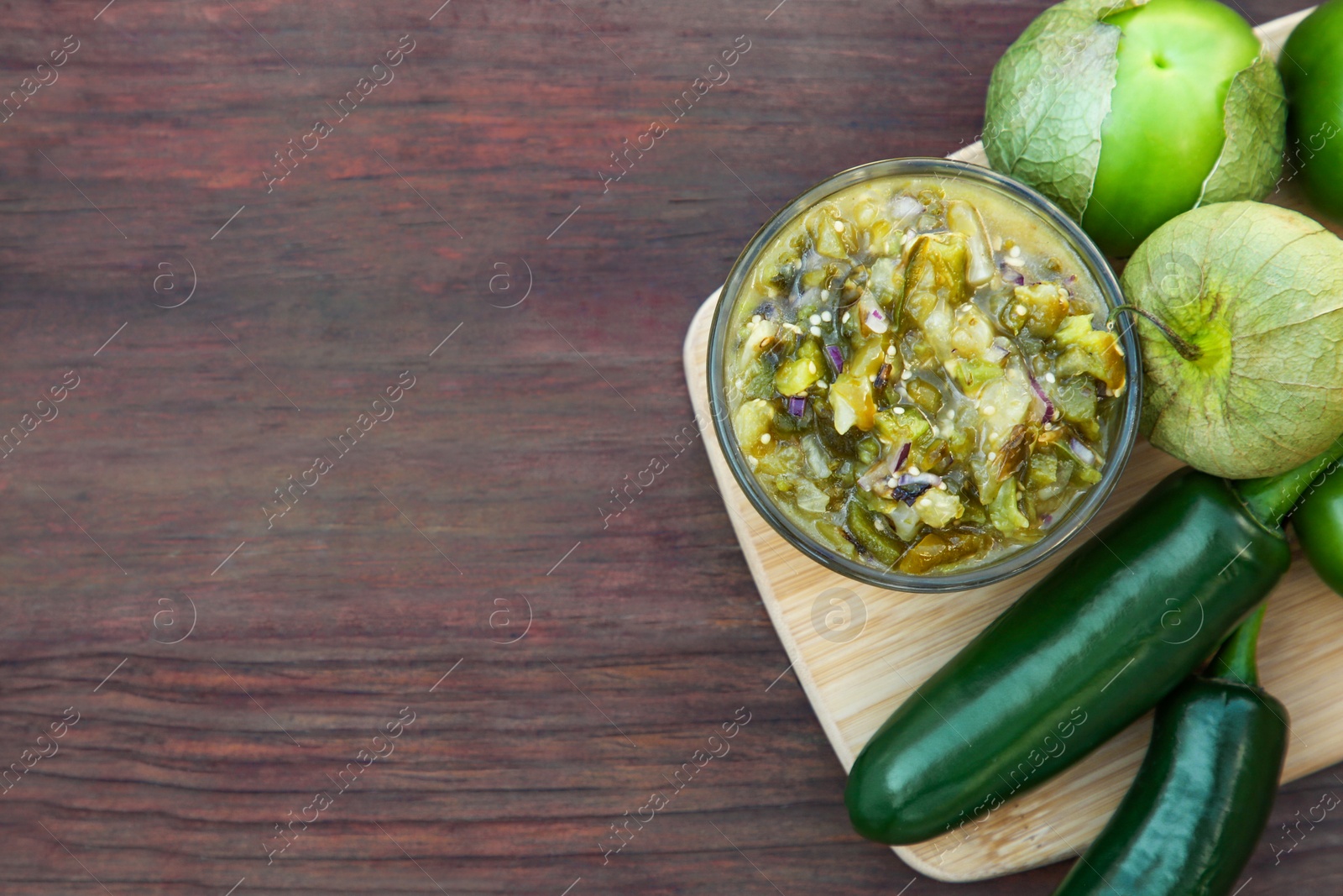 Photo of Tasty salsa sauce and ingredients on wooden table, top view. Space for text