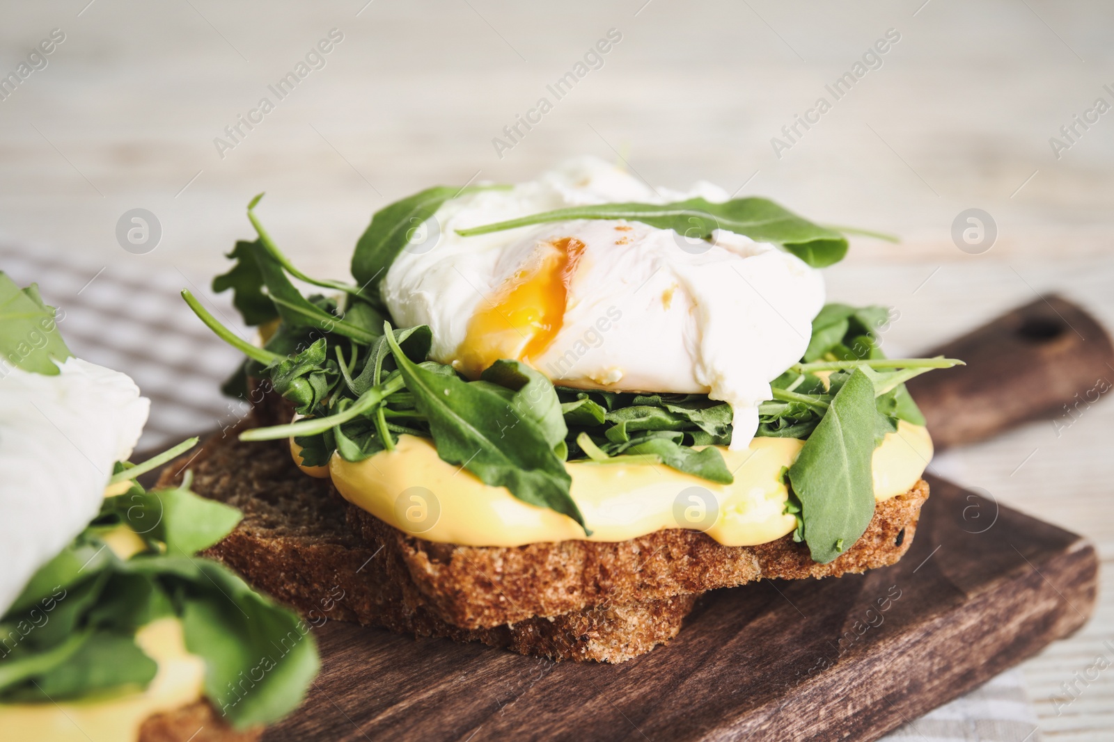 Photo of Delicious sandwich with arugula and egg on wooden board, closeup