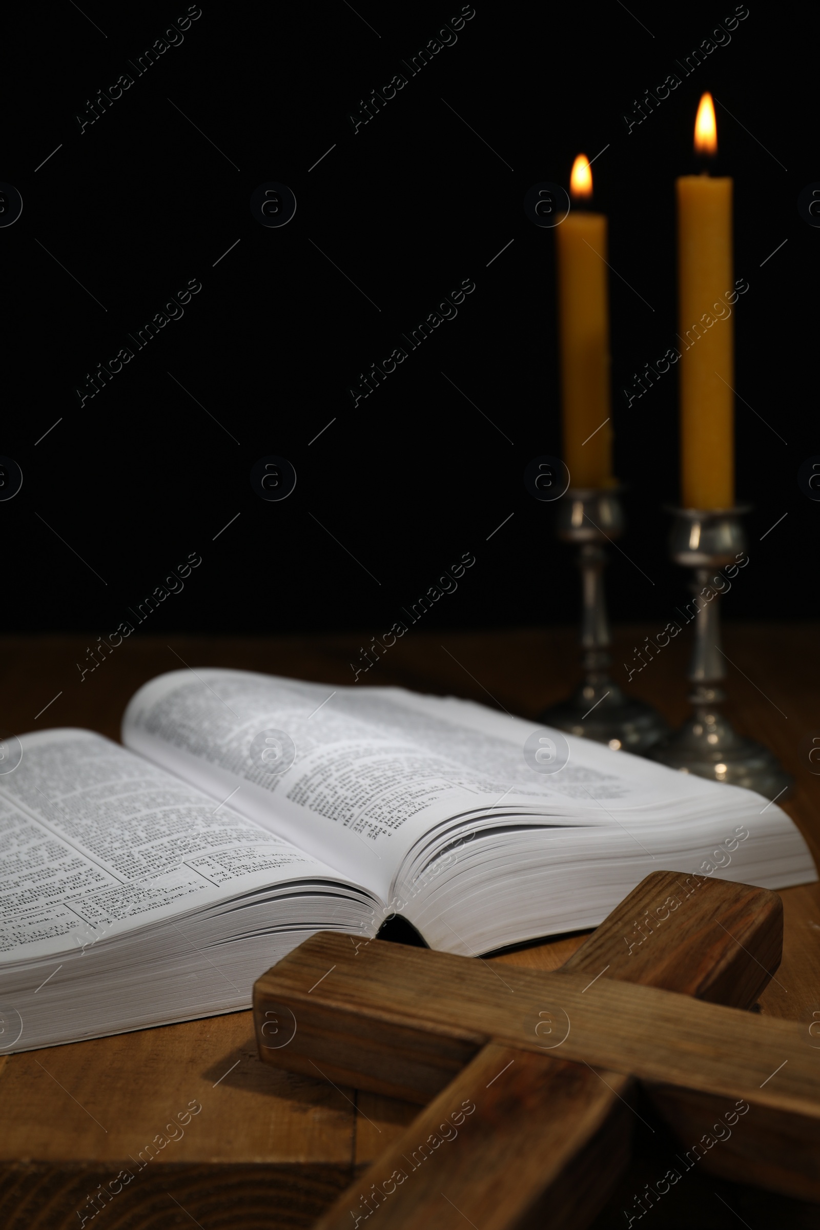 Photo of Bible, cross and church candles on wooden table