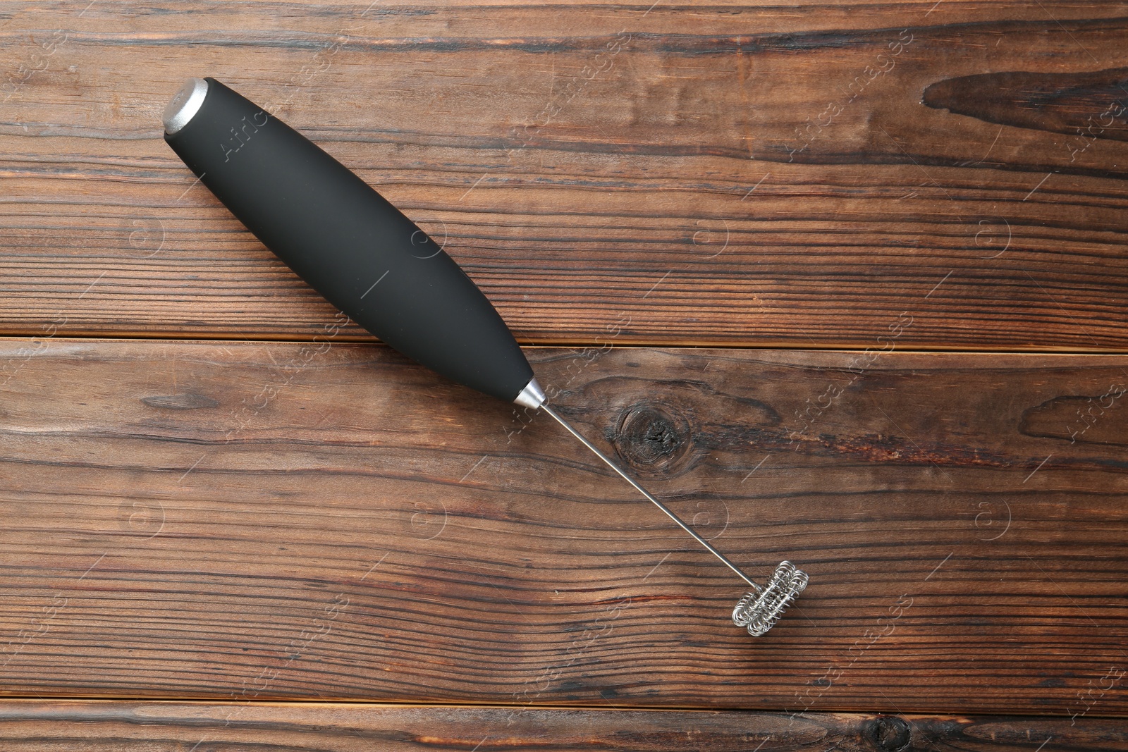 Photo of Black milk frother wand on wooden table, top view