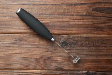 Photo of Black milk frother wand on wooden table, top view