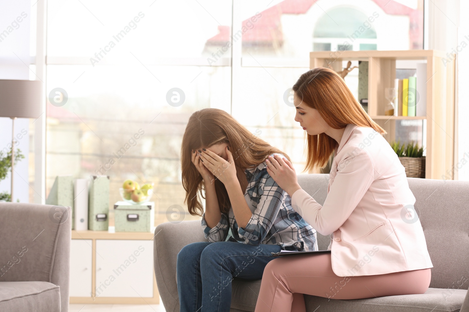 Photo of Young female psychologist working with teenage girl in office