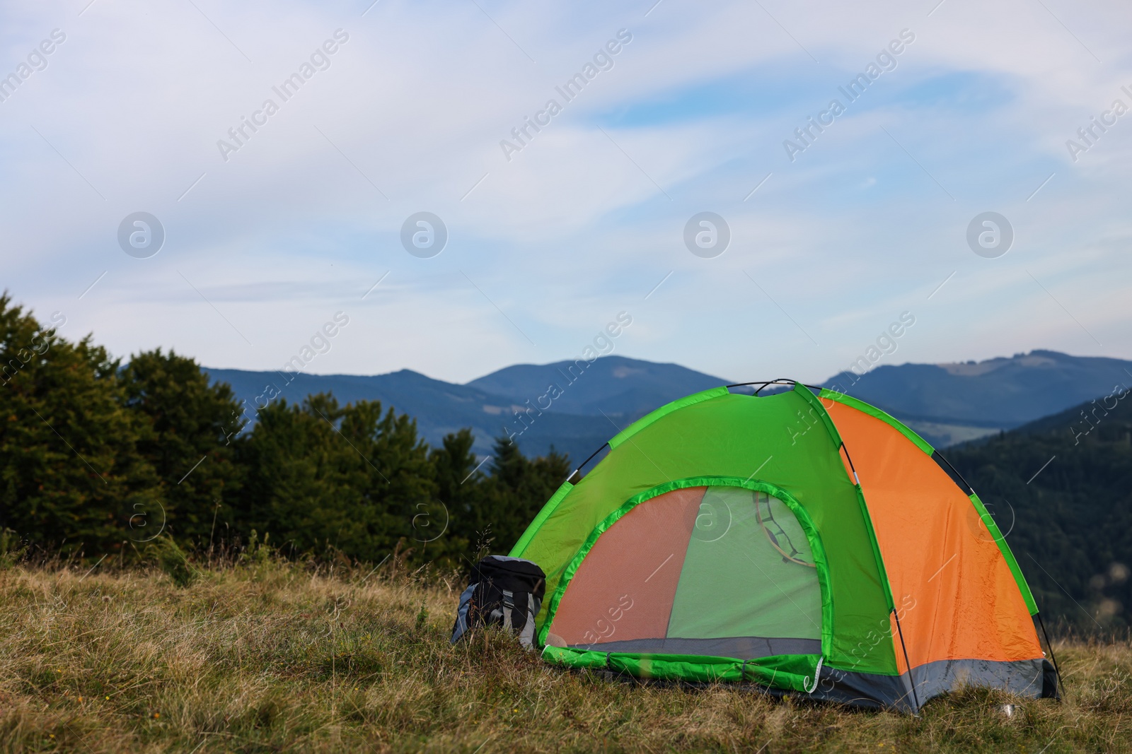 Photo of Color camping tent on grass in mountains, space for text