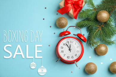 Image of Flat lay composition with alarm clock, gift and text Boxing Day Sale on light blue background